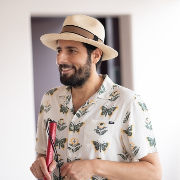 Portrait of Carmen Papalia. A man with a goatee and a white hat. He carries a white cane.