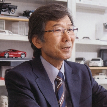 Portrait of Susumu Ouchi. A man wearing glasses and a suit. He is talking to someone looking to the right.