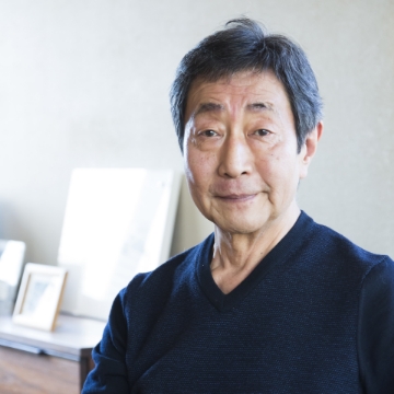 Portrait of Takashi Serizawa. A man with short hair, facing us, wearing a black shirt.