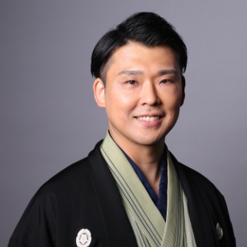 Portrait of Shunpu Tei Shokichi. A man with a short cut. He wears a beige kimono and a black haori.